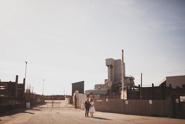 Wedding couple stood outside of a gravel factory in Whitstable after their wedding at the East Quay wedding venue in Whitstable Kent