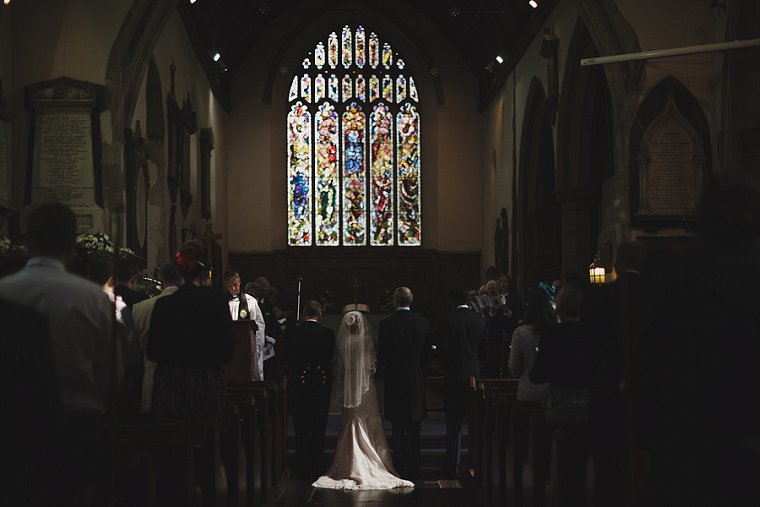 A bride and groom stood in a shaft of light at the alter of a church