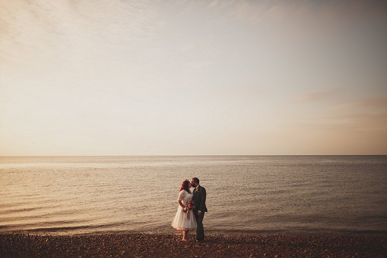 A bride and groom kissing at sunset on the beach at Whitstable in Kent following their wedding at The Lobster Shack East Quay in Kent