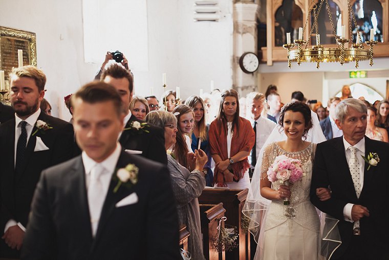 Bride entering the church and smiling at groom as she arrives for the start of her wedding ceremony
