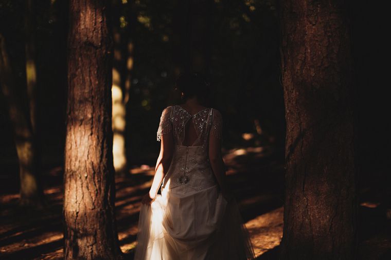 Shafts of light capturing a bride as she walks through a forest in Kent