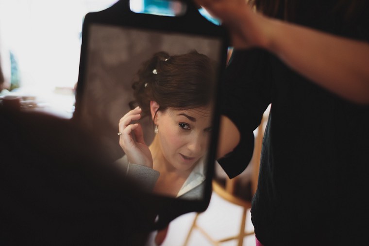 Bride looking at her hair and make up in a hand held mirror