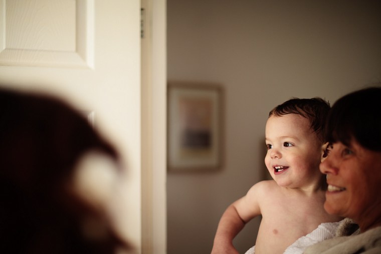 Page boy looking on and smiling as the bride gets ready for her wedding