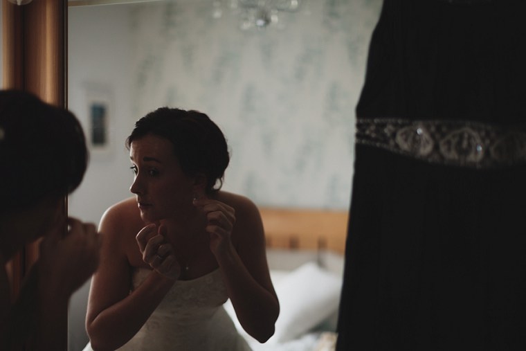 Bride putting on her wedding jewelry in a mirror