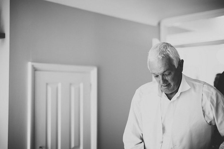 Black and White photograph of brides father as he puts on his wedding suit
