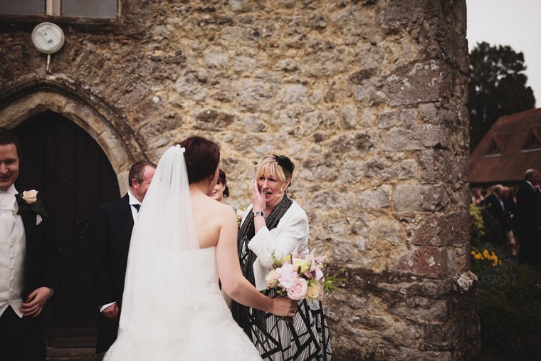 Mother of the groom hugging the bride after her wedding at St Mary's church in Kent