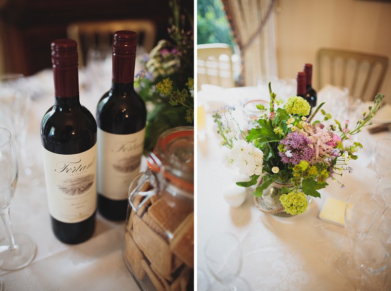 Wedding Flowers and bottles of red wine on the tables at the wedding of Simon and Laura