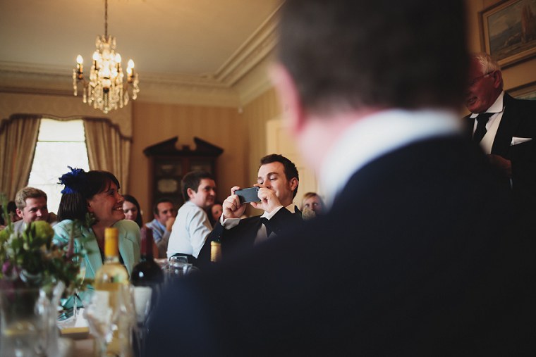 Best man taking a photograph during wedding speeches