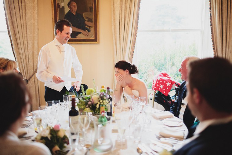 Bride laughing as her husband gives his wedding speech