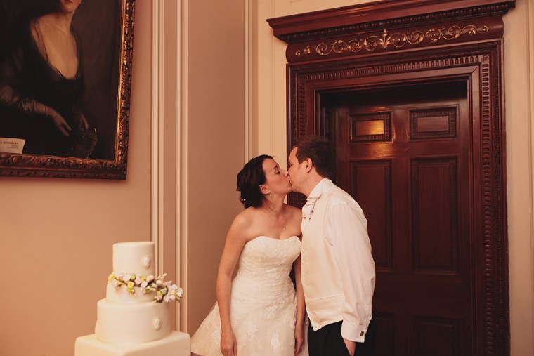 Couple kiss before cutting the wedding cake at Mount Ephraim Gardens in Kent