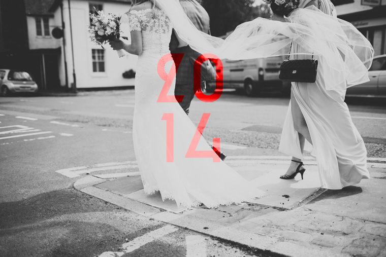 Black and white photography of a bride holding her bouquet walking through Lenham to her Tithe Barn wedding. Photographed by Kent Wedding Photographer Paul Fuller